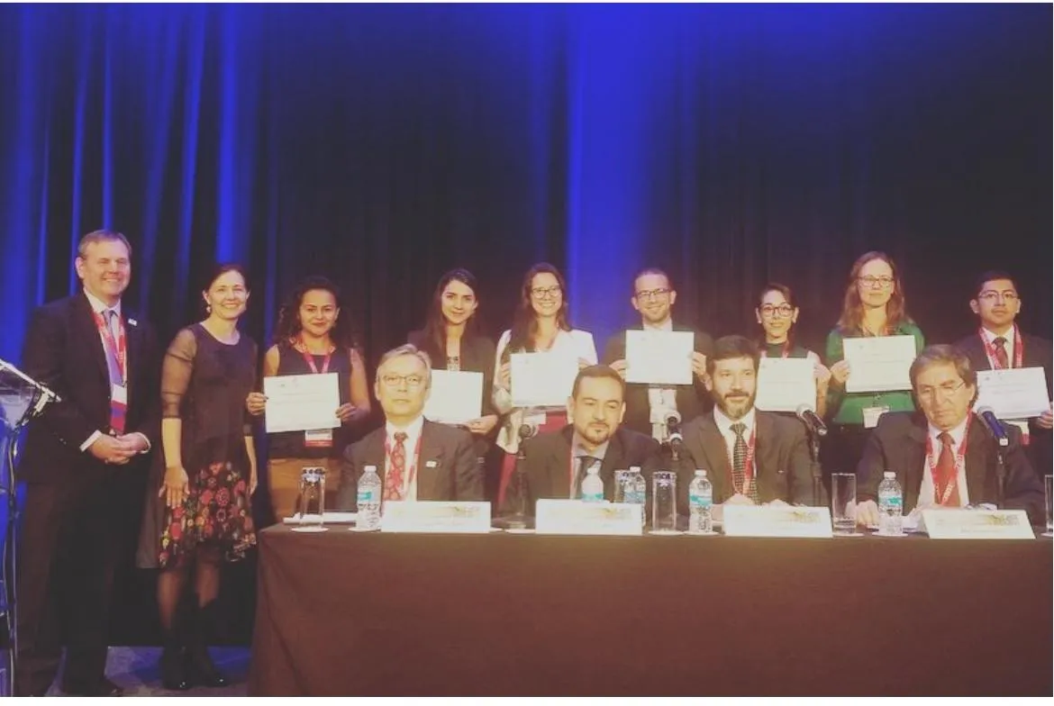 Premiados e membros da mesa no palco da cerimônia de premiação da LALCA 2019, segurando certificados
